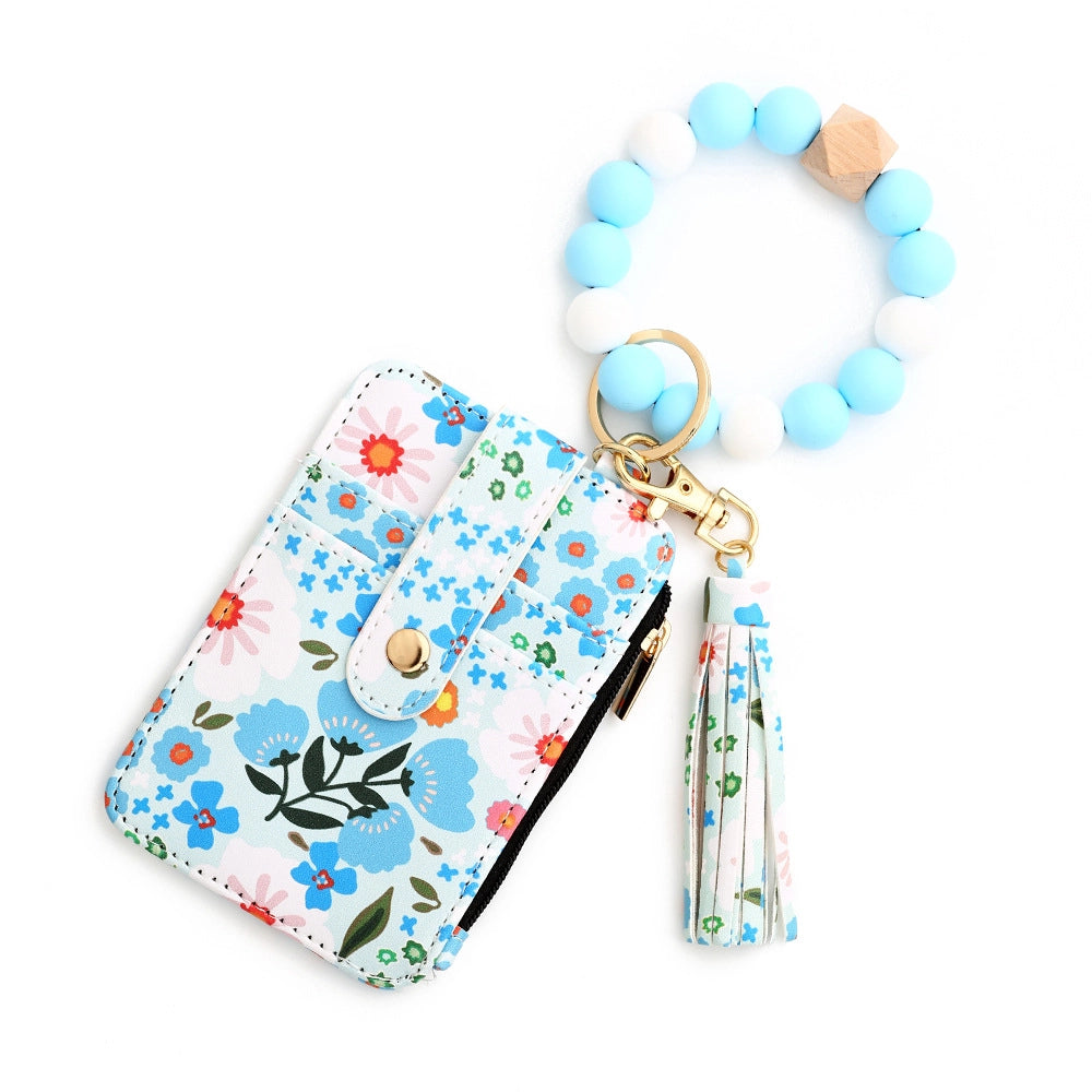 Blue floral card holder wristlet by MKS America with light blue and white beaded bracelet keychain, matching tassel, and zip pocket.