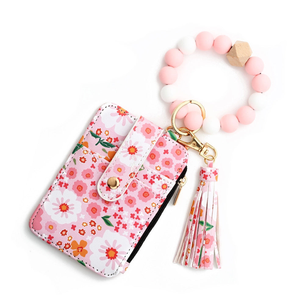 Pink floral card holder wristlet by MKS America with pink and white beaded bracelet keychain, matching tassel, and zip pocket.